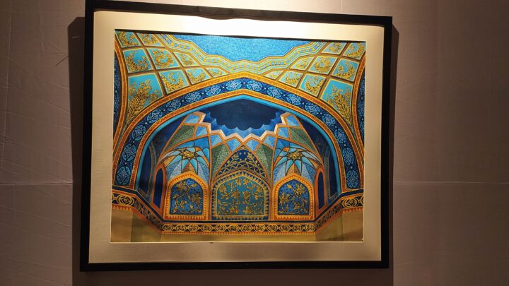 A framed artwork from the Fine Arts College in Shantiniketan depicts an ornate archway with intricate blue and gold Islamic geometric patterns. The archway features a symmetrical design with elaborate detailing and vibrant colors. The black-framed piece is mounted on a plain white wall.